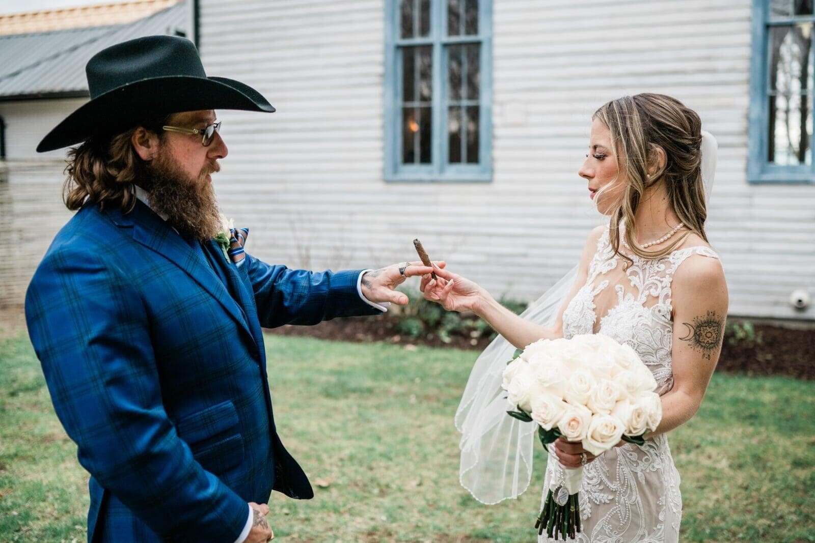Outdoor setting, the bride standing on the right is passing a blunt to the groom standing on the left